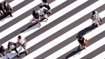 Een bovenaanzicht van een zebrapad met mensen die oversteken