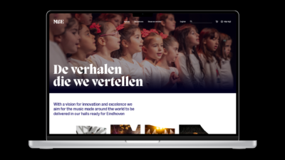 Een laptop met de website van Muziekgebouw Eindhoven open, met een headerafbeelding van zingende kinderen.
