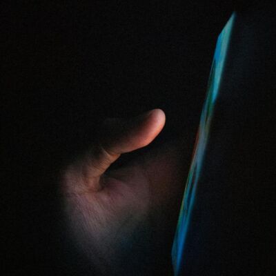 Iemand die in het donker op zijn mobiele telefoon navigeert.