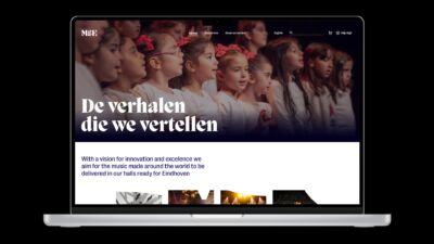 Een laptop met de website van Muziekgebouw Eindhoven open, met een headerafbeelding van zingende kinderen.