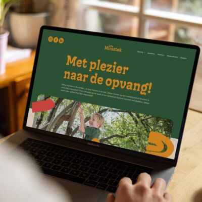 Een laptop met de homepage van Ministek in groen en oranje.